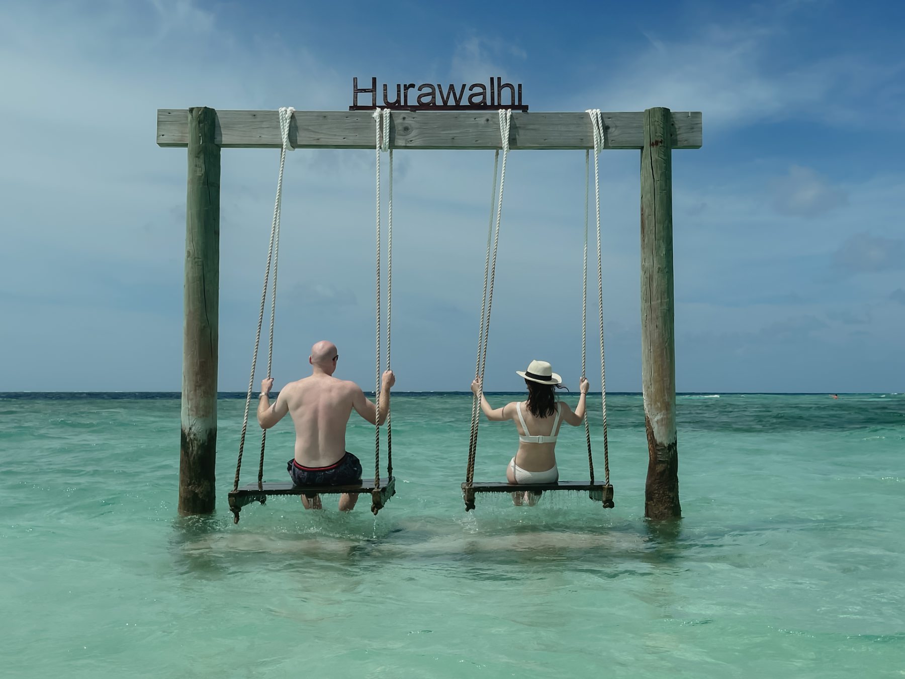 honeymoon reviews the maldives hurawalhi island resort beach scene with swings over the ocean and just married couple sitting on them