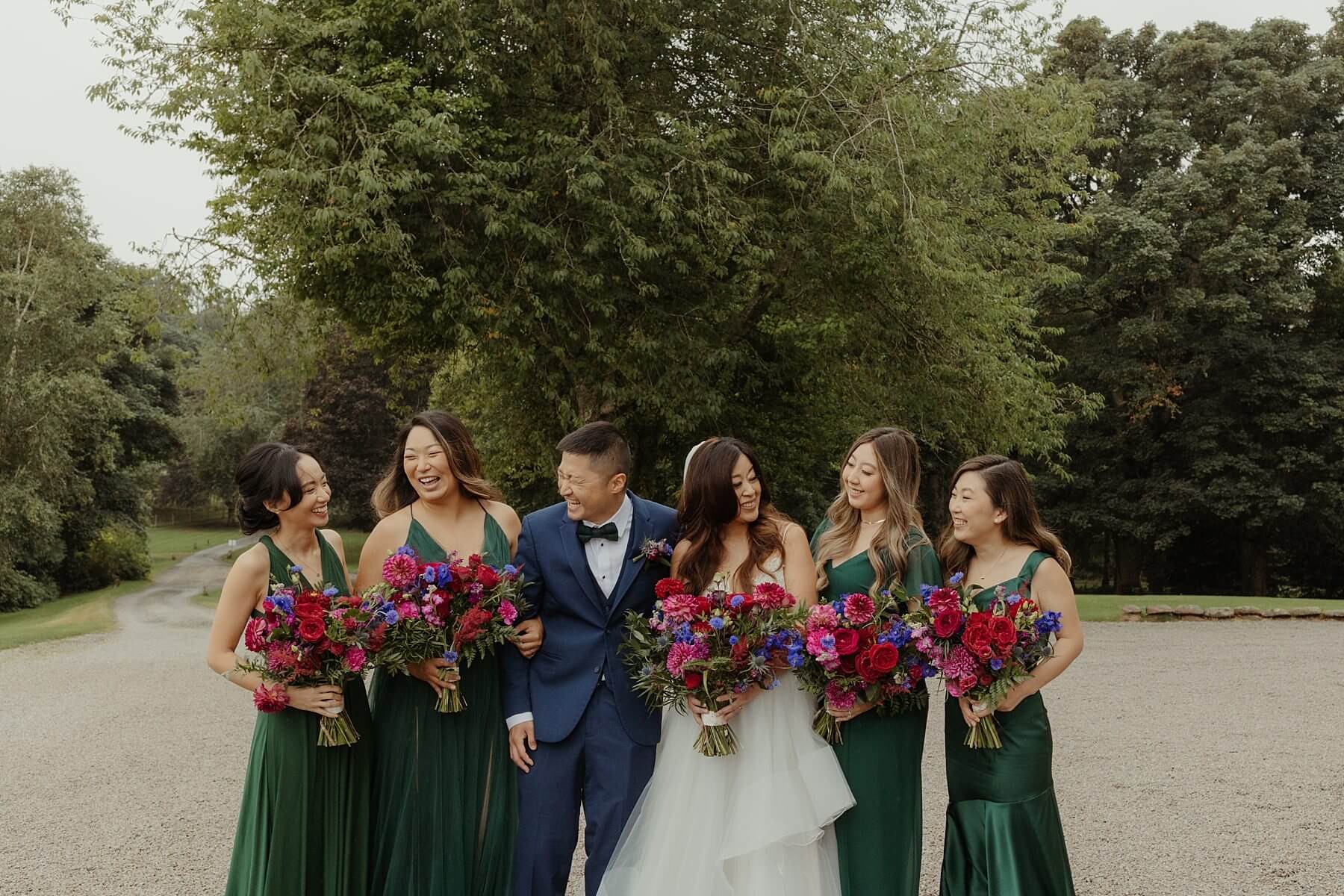american bride and groom pose with wedding party bridesmaids in green silk dresses at cluny castle wedding scotland